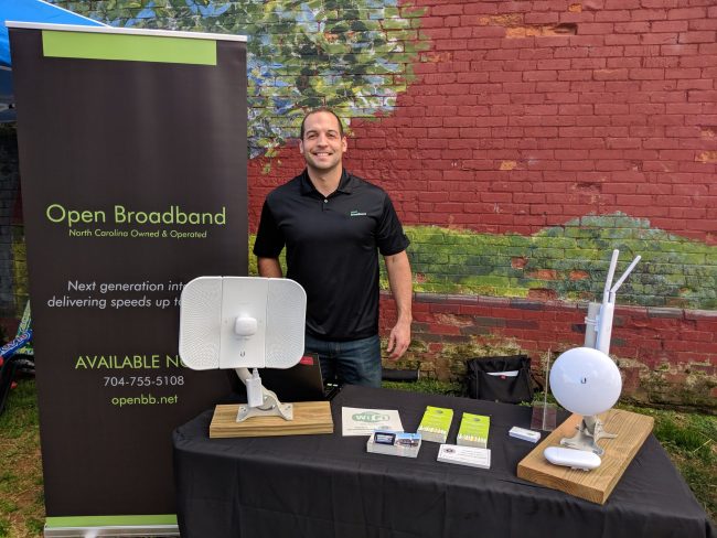 Man standing with open broadband banner and table full of devices and flyer