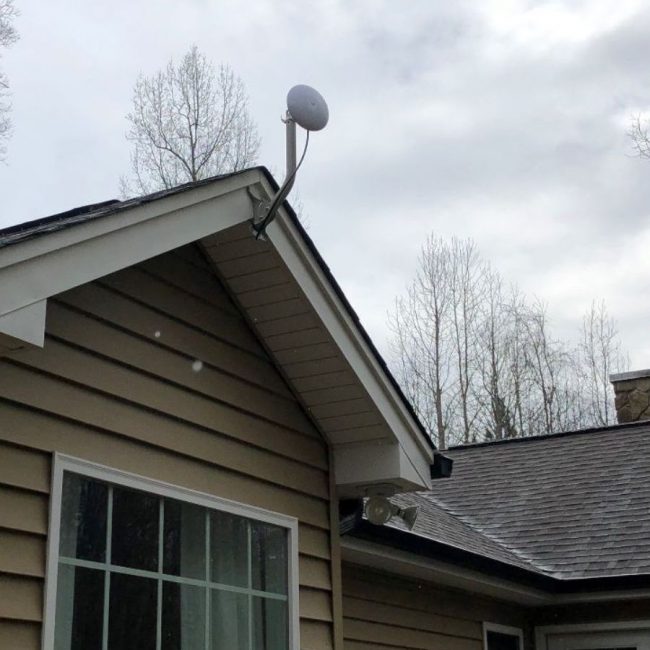 Dish attached to peak of roof of brown house
